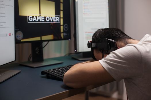 Man keeping his head on the office after losing at shooter games on the stream. Game over for professional gamer.