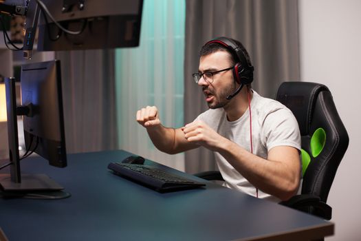 Young man with headphones yelling after his victory at online shooter game.