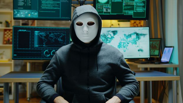 Dangerous hacker hiding his identity wearing a white mask while using augmented reality to steal confidential data.