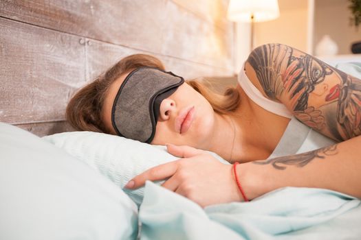 Attractive girl in bedroom sleeping with eye cover mask. Caucasian woman.
