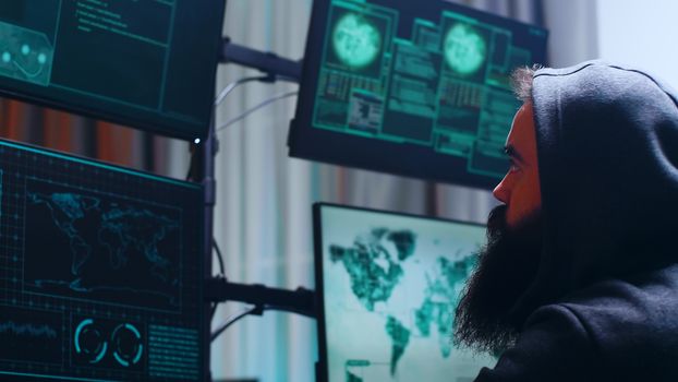 Side view of bearded cyber terrorist wearing a hoodie. Dangerous cyber criminal.