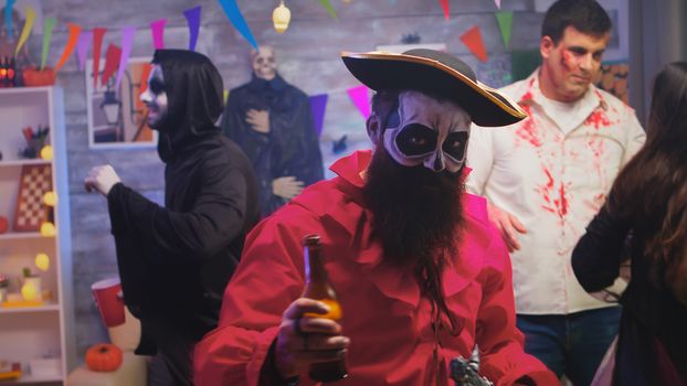 Bearded man dressed up like a pirate celebrating halloween with a group of friends disguised like different monsters