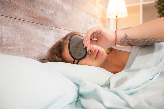 Beautiful lady sleeping with eye cover with head on pillow in bedroom.