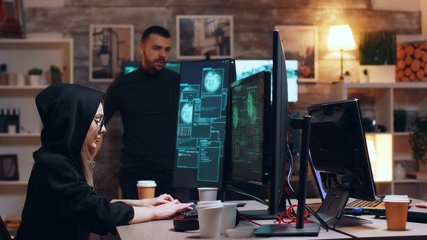 Girl hacker wearing glasses and a hoodie while stealing personal data with her team.