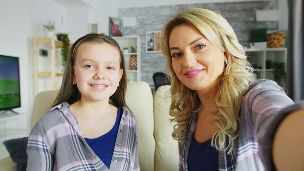 Pov of happy daughter with braces and her mother making funny faces in front of camera.