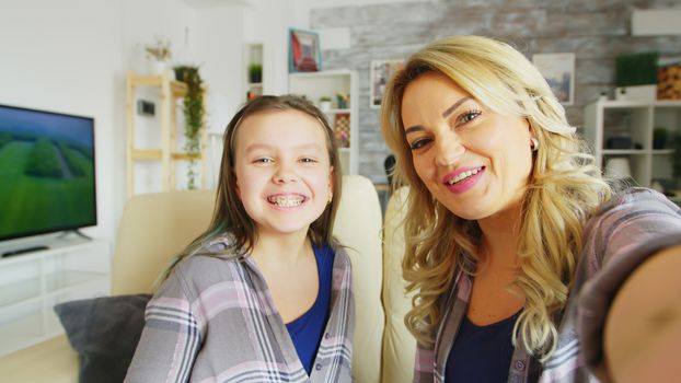 Pov of little girl showing her braces to the camera sitting next to her beautiful young mother.