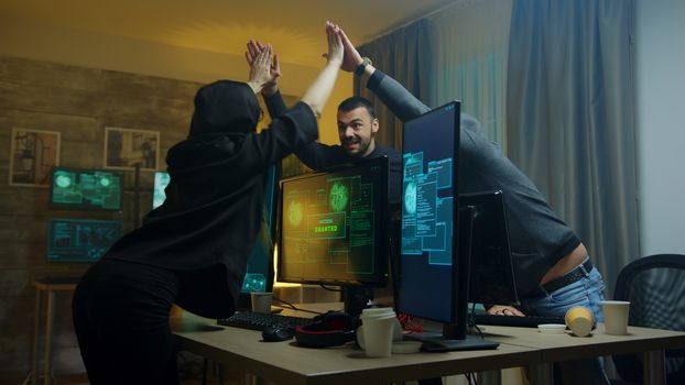 Team of cyber criminals celebrate after a successful hack on government server. Hacker girl.