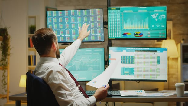 Bearded stock market trader taking a sip of coffee while reading a graph about financial decline.