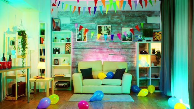 Party decorated room with neon lights on the wall and a disco ball, drinks, balloon and chips.