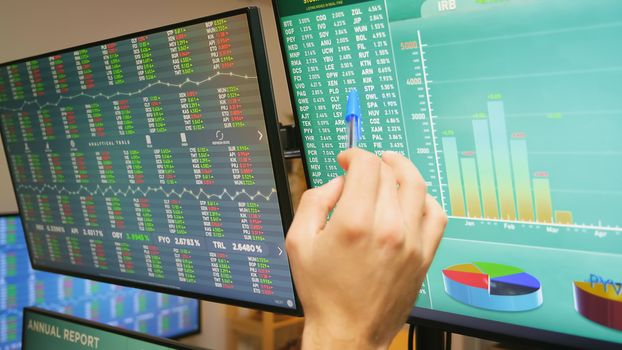 Close up of stock market trader hand on monitors with financial graphs. Economy crash.