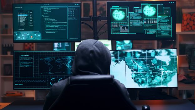Back view of male hacker wearing a hoodie infecting government server with a dangerous virus.
