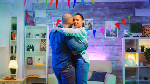 Attractive young couple dancing on romantic music at home.