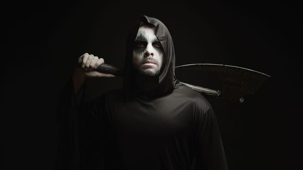 Grim reaper over black background with axe in his hands. Halloween costume.