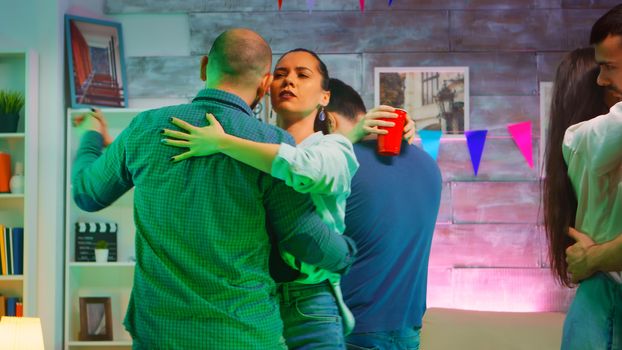 Young beautiful couples dancing on romantic music at the party. Neon light.
