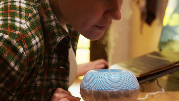 Adult woman inhale steam from air purifier. Aromatherapy device.