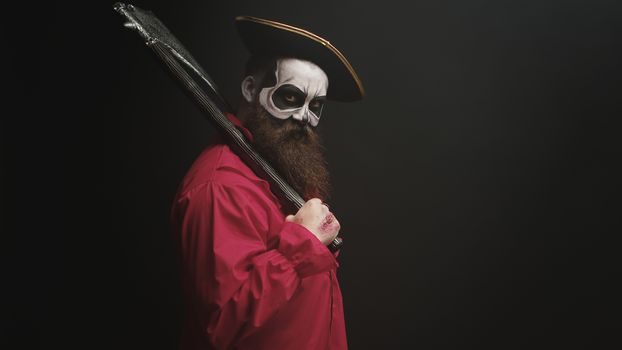 Crazy man with make up dressed up like pirate with an axe for halloween party.
