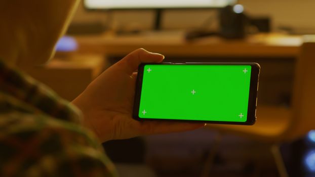 Back view of woman using smartphone with green screen mock-up