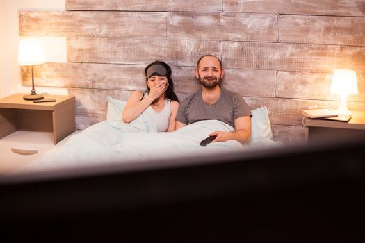 Emotional couple in pajamas while watching a movie on tv.