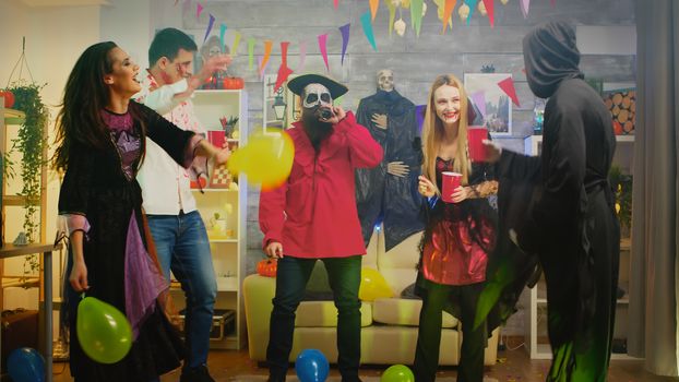 Group of people dancing and having fun at Halloween party in a decorated house. Repear, zombie, witch and pirate