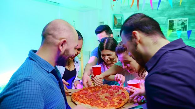 Follow shot of young man arriving at wild college party with delicious pizza.