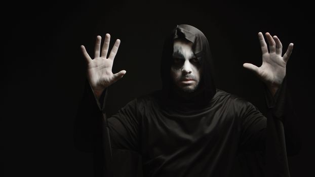 Young man with scary make up dressed up like grim reaper for halloween.