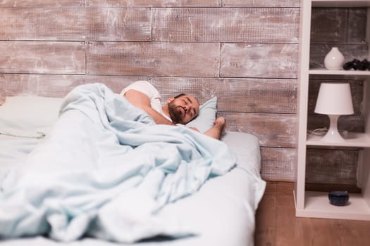 Tired man sleeping on comfortable bed having a good dream.