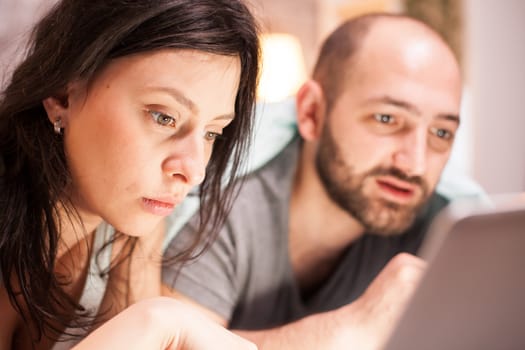 Close up of married young couple wearing pajamas using laptop for shopping during quarantine.