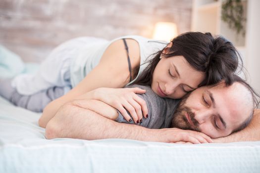 Beautiful caucasian woman in pajamas sleeping on boyfriend back in the morning.