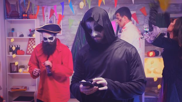 Bored young man dressed up like grim reaper at halloween party.