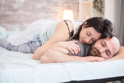 Cheerful woman in pajamas sleeping with her boyfriend on comfortable bed.