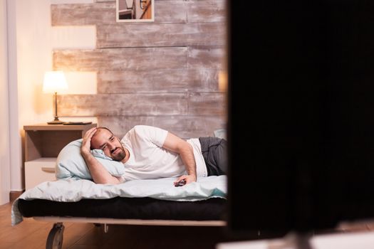 Man with suffering anxiety watching tv late at night.