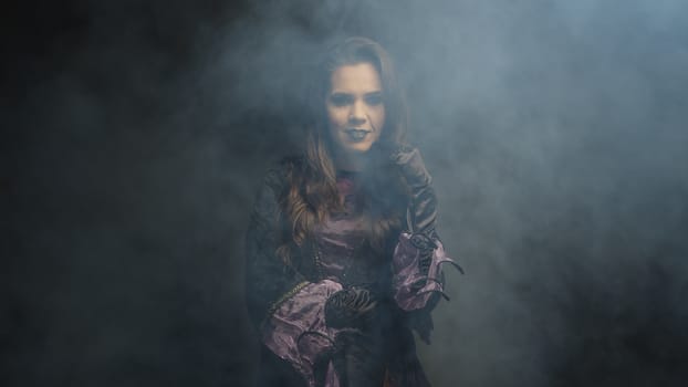 Beautiful young woman dressed up like a witch for halloween over black background.