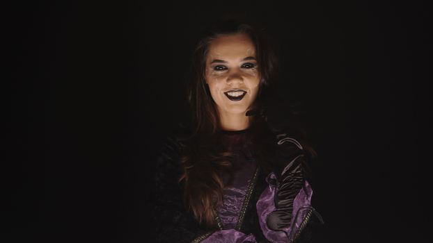 Scary woman dressed up like a witch for halloween over a black background