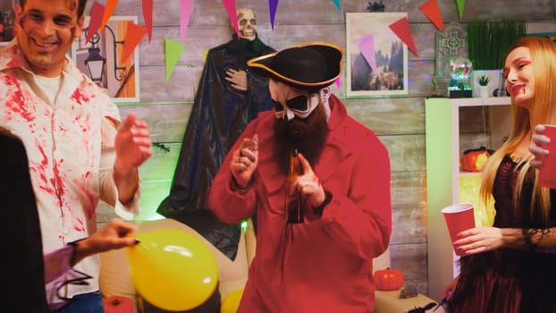 Crazy Halloween party with different funny and scary characters dancing in decorated room. Witch, repear, pirate and zombie