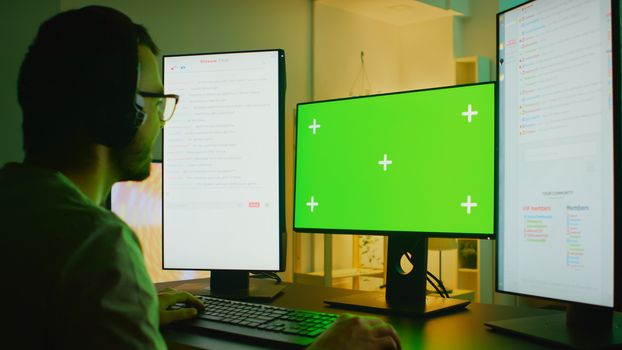 Young man streaming his online gaming on powerful computer with green screen. Talking with multiple players.