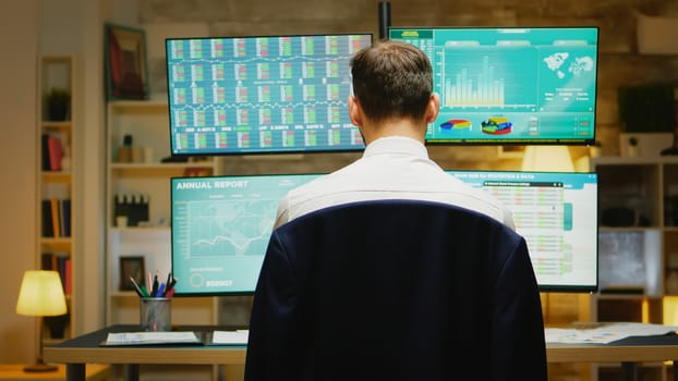 Portrait of financial broker turning and looking at the camera while checking the stock market from home office.