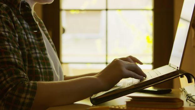 Silhouette of freelancer woman working from home on modern laptop.