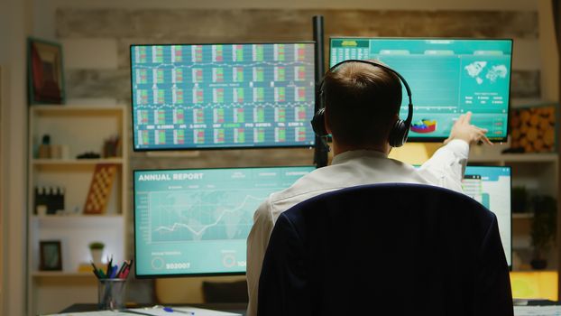 Excited stock market trader with hands up celebrating a big sale in times of stock market crash. Multiple displays with real time trading data