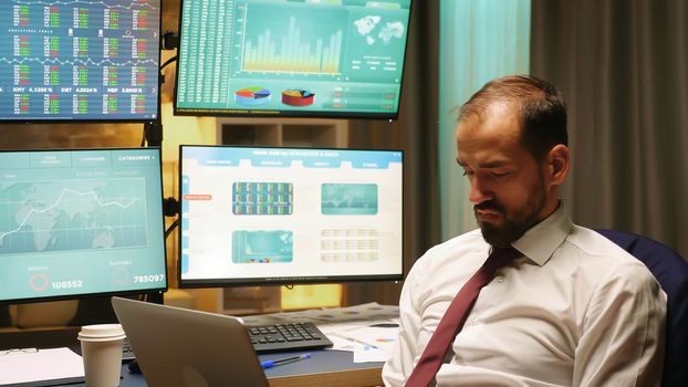 Businessman wearing suit and tie working on laptop checking the stock market crash.