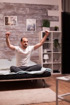 Excited man in bedroom watching sports on big tv.