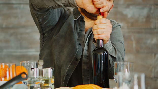 Close up shot of man opening a bottle of red wine for his family at lunch.