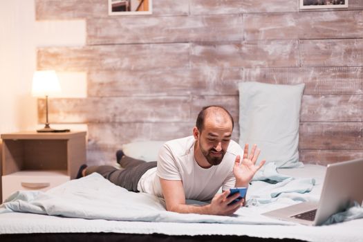 Man receiving a video call late at night while relaxing in bedroom