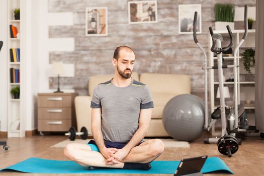 Man in shape watching online yoga class during covid-19 lockdown.