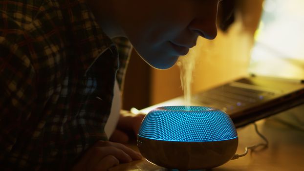 Woman inhale aromatic vapor from essential oil diffuser while working in the kitchen