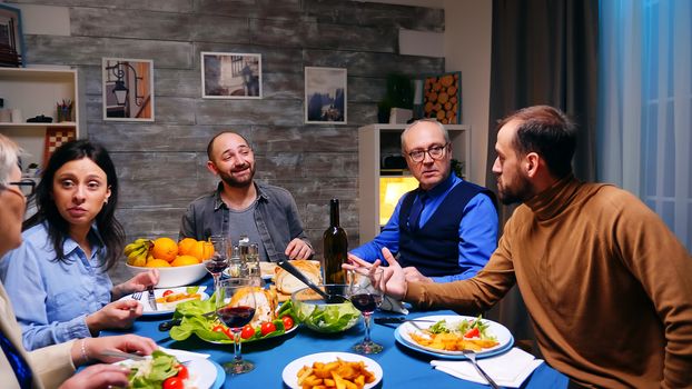 Two sons having a conversation with their father at dinner. Delicious food.