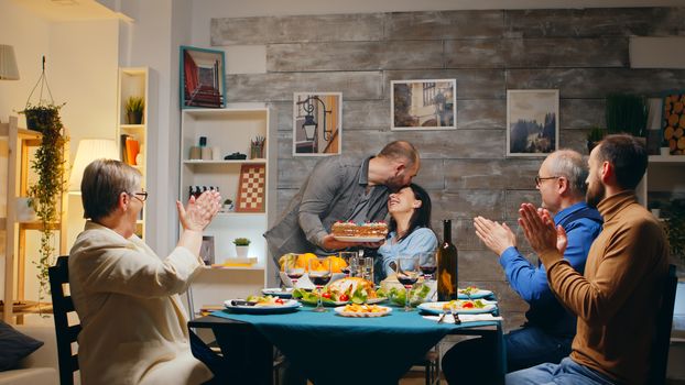 Woman and dinner with friends and family having a surprise with cake. She blows the candles. Slow motion shot