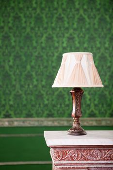 Vintage lamp on chimney on green retro pattern background. Rococo style