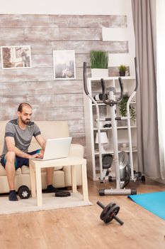 Man in sportswear searching body exercise on laptop during global pandemic.