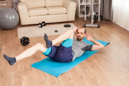 Athletic man training his abdomen on yoga mat during global pandemic.