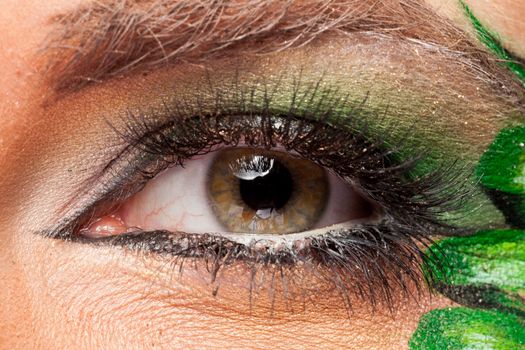 Close up of an eye with green artistic make up in studio photo